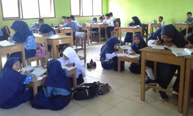 Tampak sejumlah siswa-siswi belajar di lantai di kelas mereka