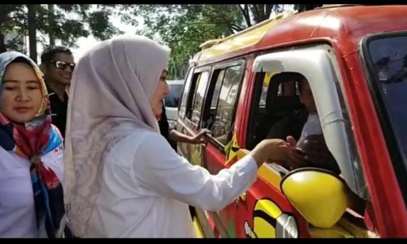 Bupati Luwu Utara, Indah P Indriani sedang membagikan bunga kepada para pengemudi dan sopir angkot. Minggu (1/12).