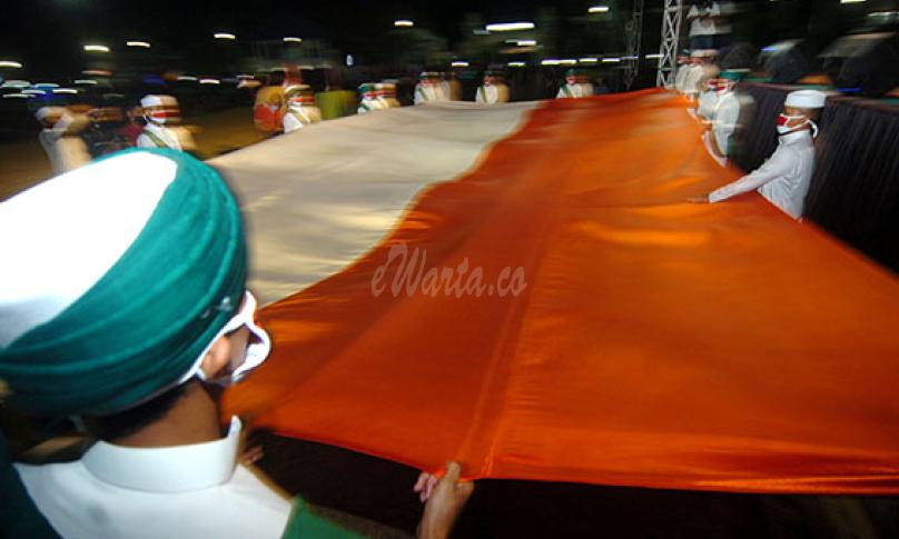 Sejumlah santri membentangkan bendera Merah Putih berukuran besar saat Kirab Merah Putih di Tegal, Jawa Tengah, Senin (17/8/2020) malam. (antarafoto)