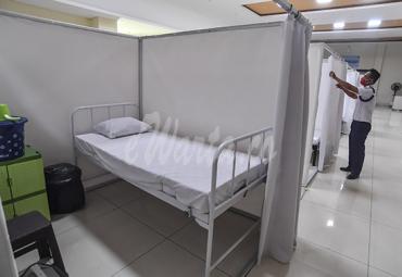 Petugas merapikan ruang isolasi mandiri pasien Covid-19 di Gelanggang Remaja Kecamatan Pademangan, Jakarta, Minggu (27/9/2020). (antarafoto)