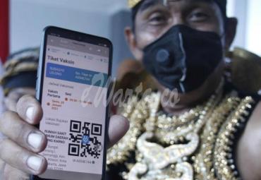 Penerima vaksin berkostum wayang Partika Subayo Lelono menunjukkan tiket elektronik penerima vaksin COVID-19 produksi Sinovac di Rumah Sakit Umum Daerah (RSUD) Bung Karno, Solo, Jawa Tengah, Jumat (22/1/2021). - (antarafoto)